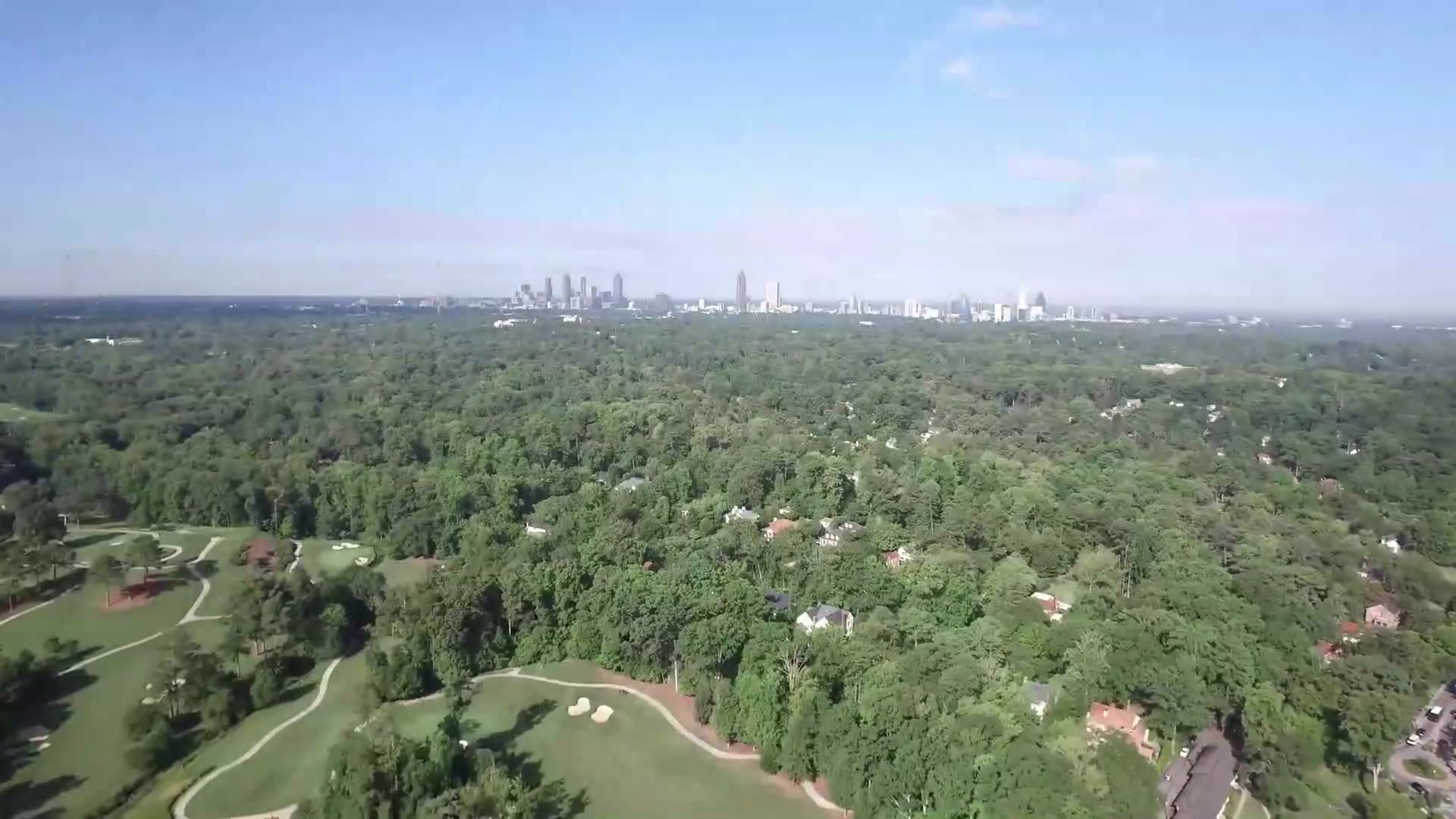 Aerial view over Atlanta's tree canopy toward the city skyline